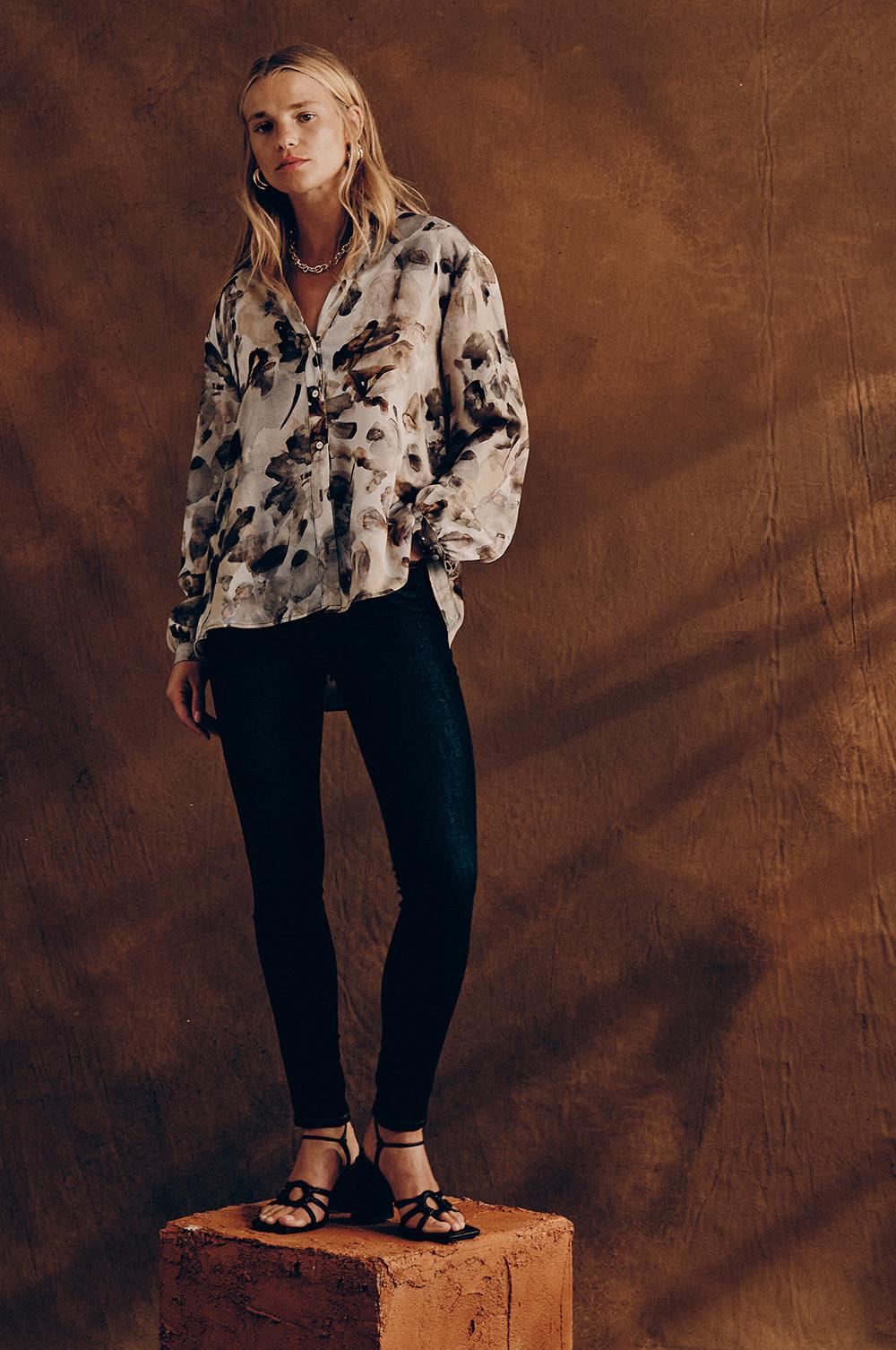 Model in gebloemd overhemd, gecombineerd met zwarte jeans en sandalen