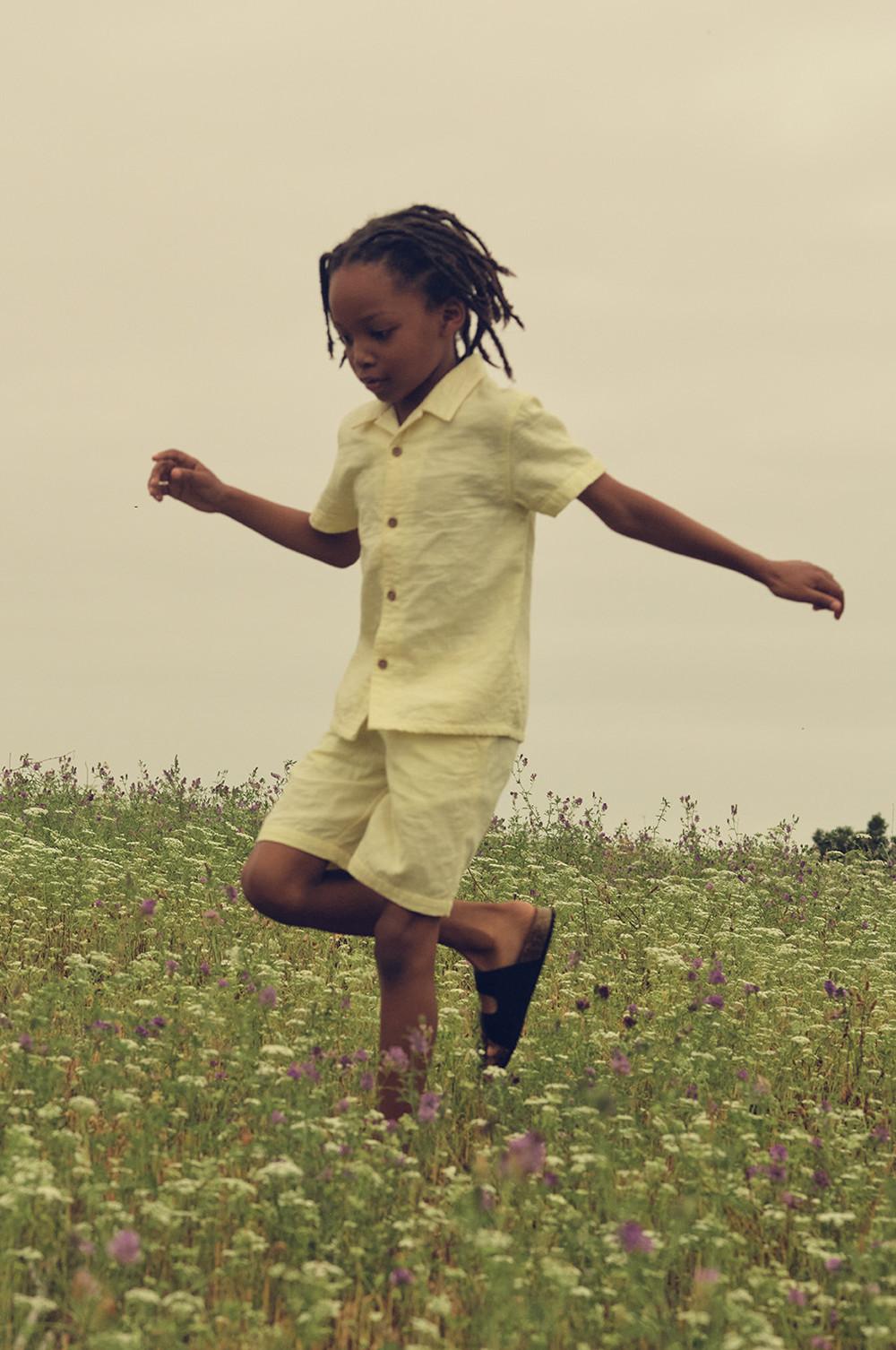 Child wearing a yellow shirt and shorts co-ord with shoes