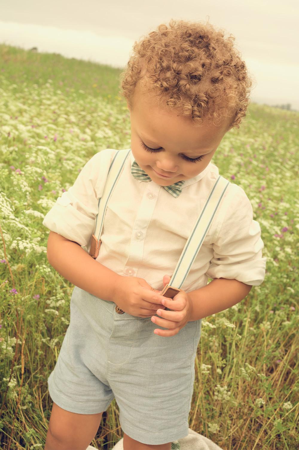 young child wearing a white shirt, bow tie and blue shorts