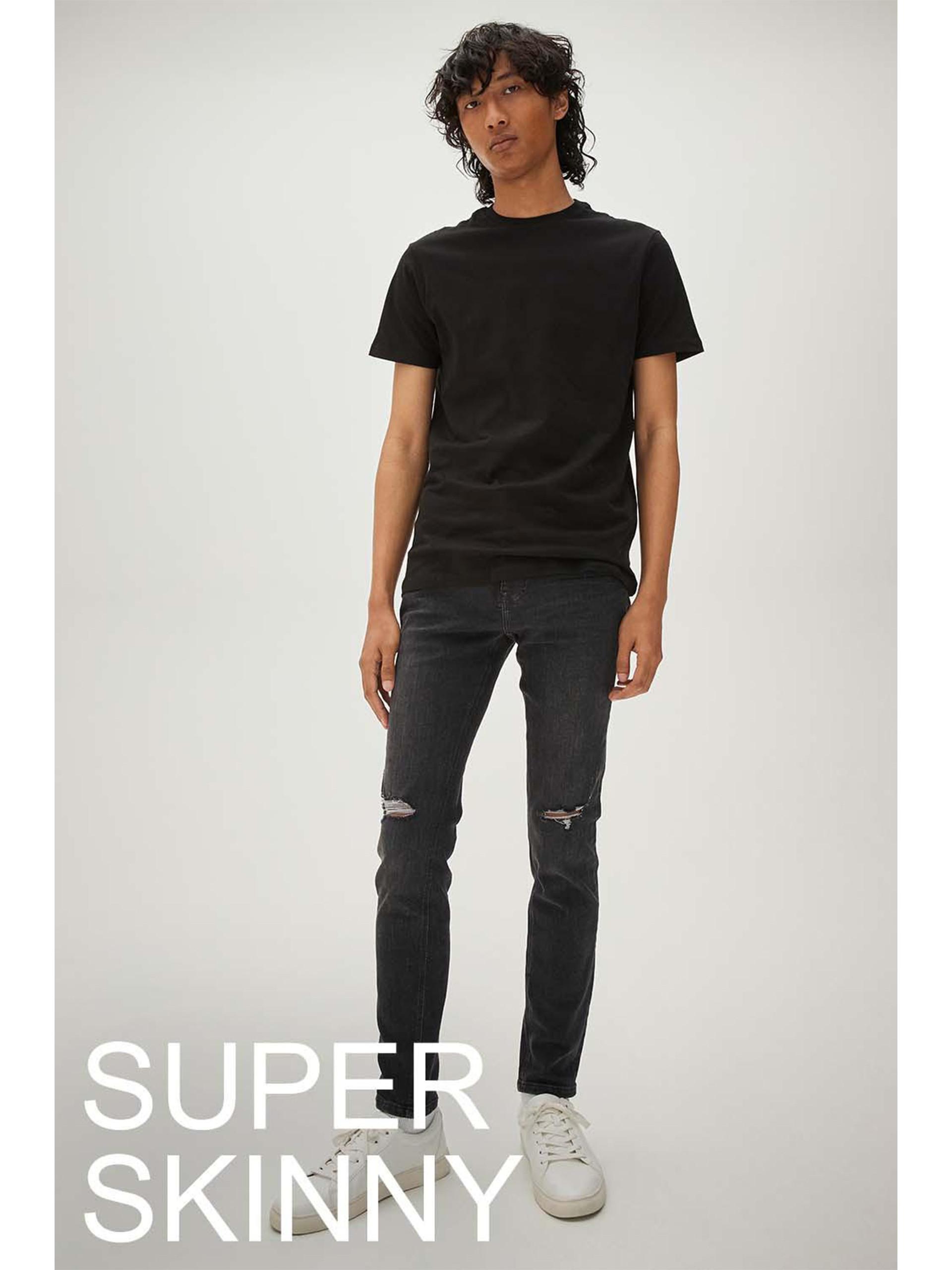 Model trägt schwarze Super Skinny Jeans mit Cuts am Knie