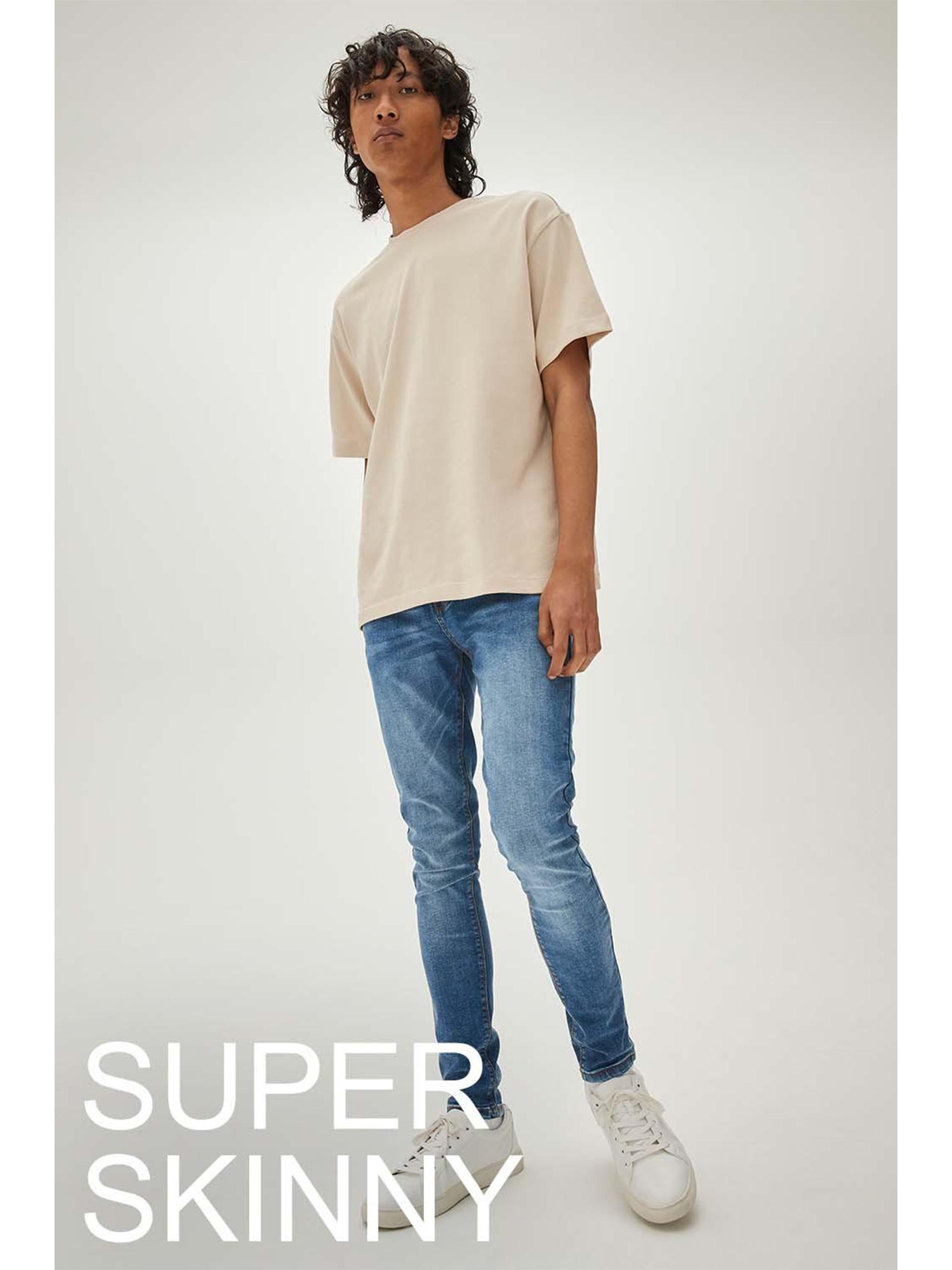 Model trägt blaue Skinny Jeans und T-Shirt im Oversized-Look in Steingrau