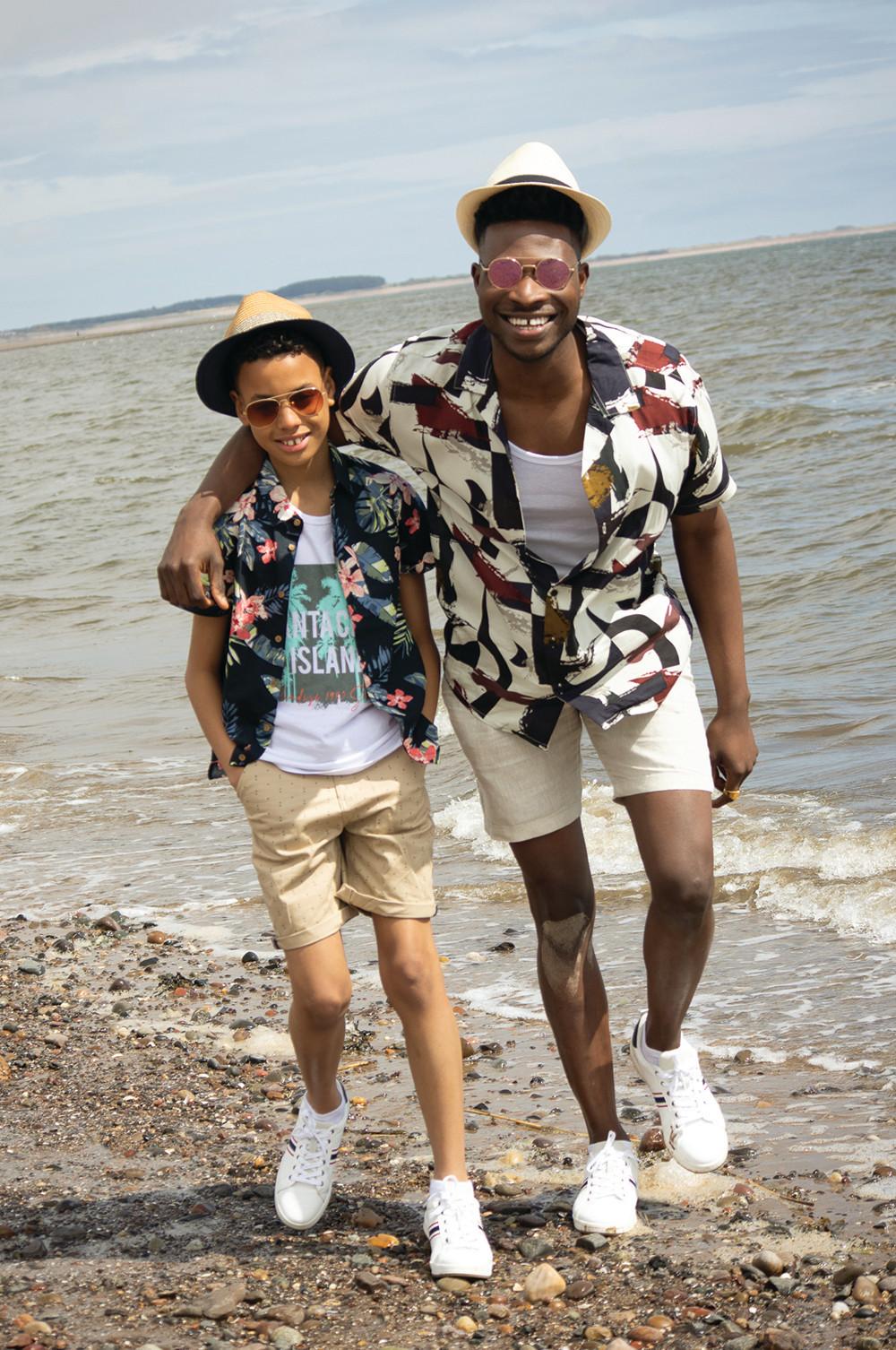 Male models wearing bold print shirts and shorts on beach
