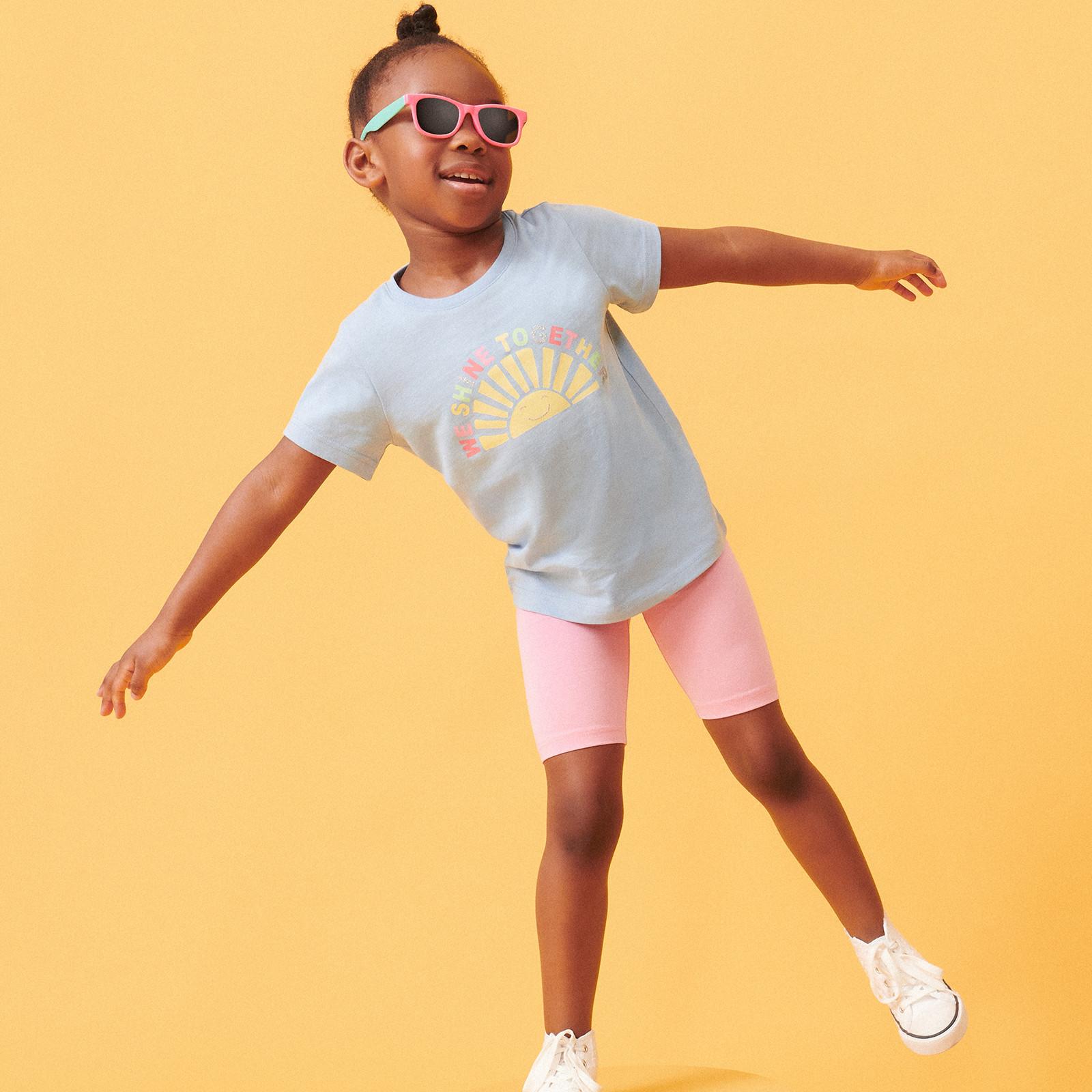 Enfant portant un T-shirt bleu et un short rose