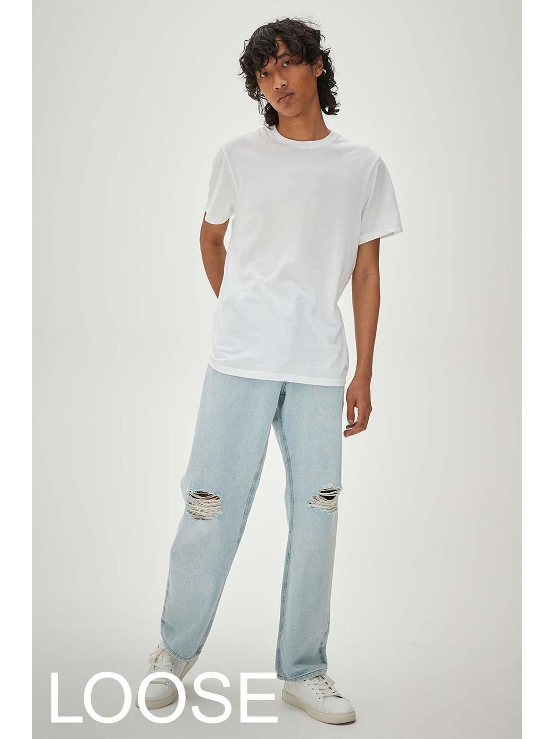Model wears light blue loose ripped jeans