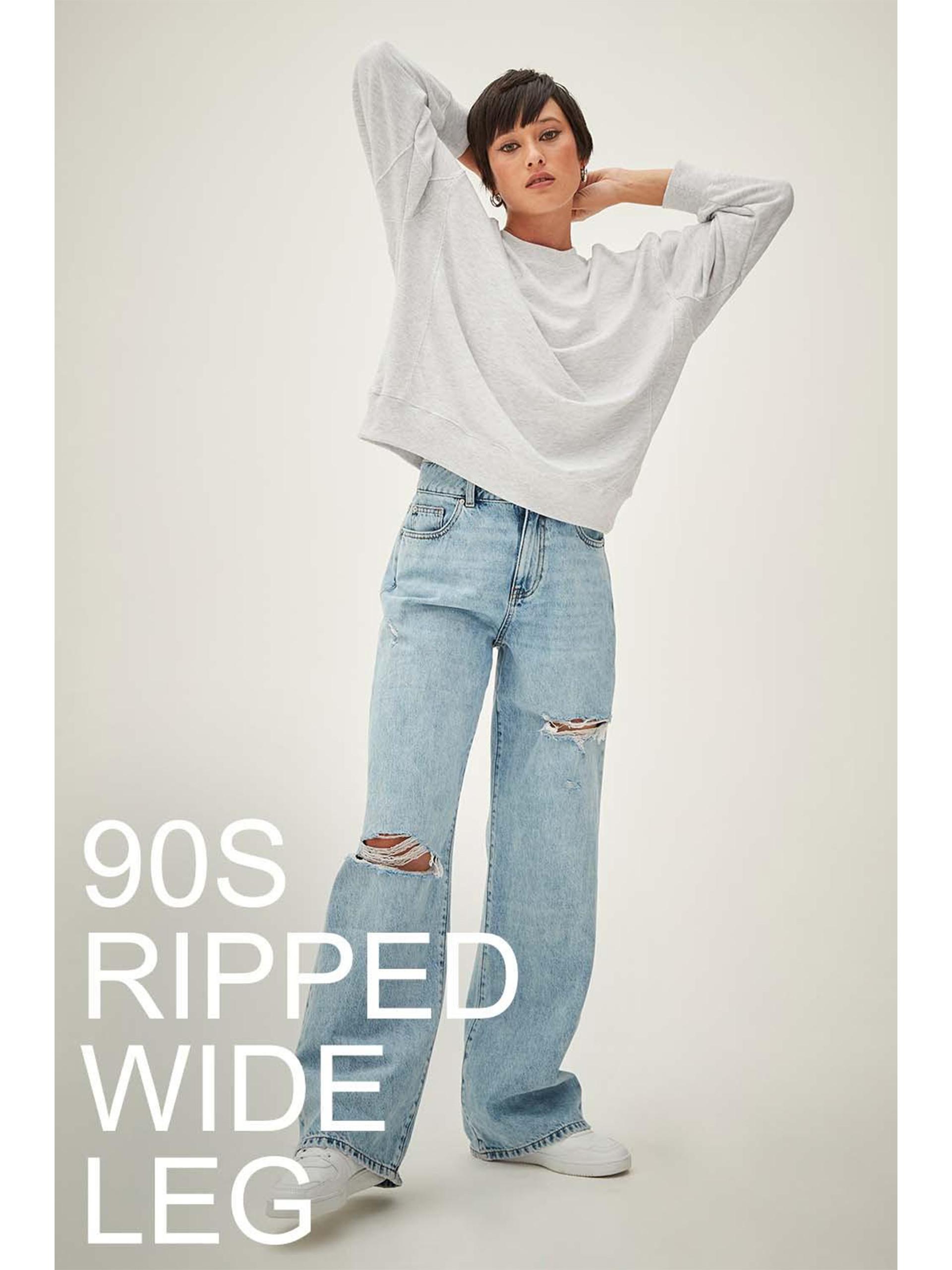 Model wears ripped wide leg jeans