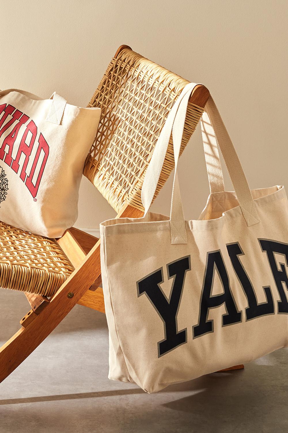 Canvas tote bags with Yale and Harvard logos in blue and red