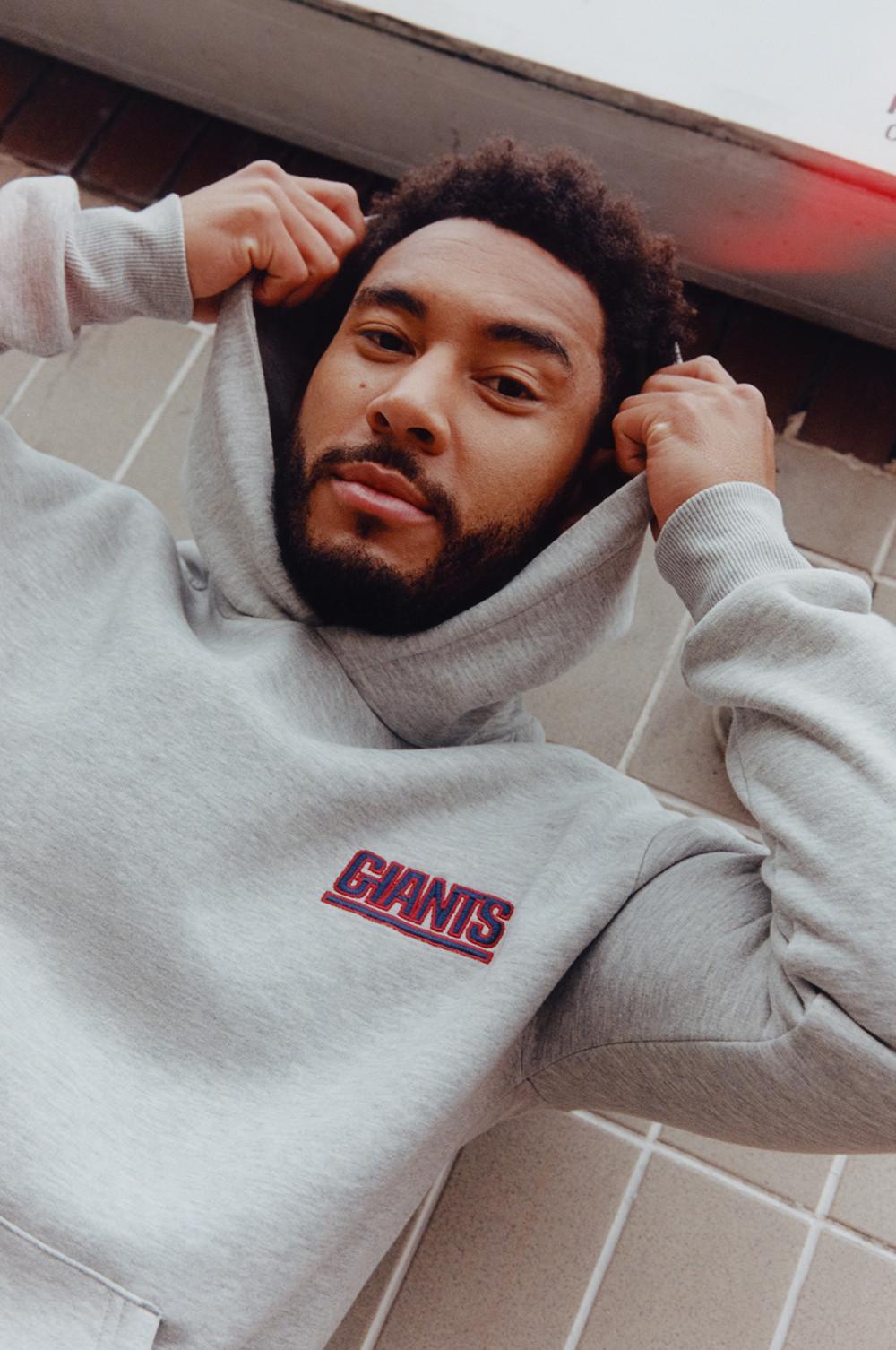 Josh Denzel trägt einen grauen NFL Kapuzenpullover mit rotem Logo