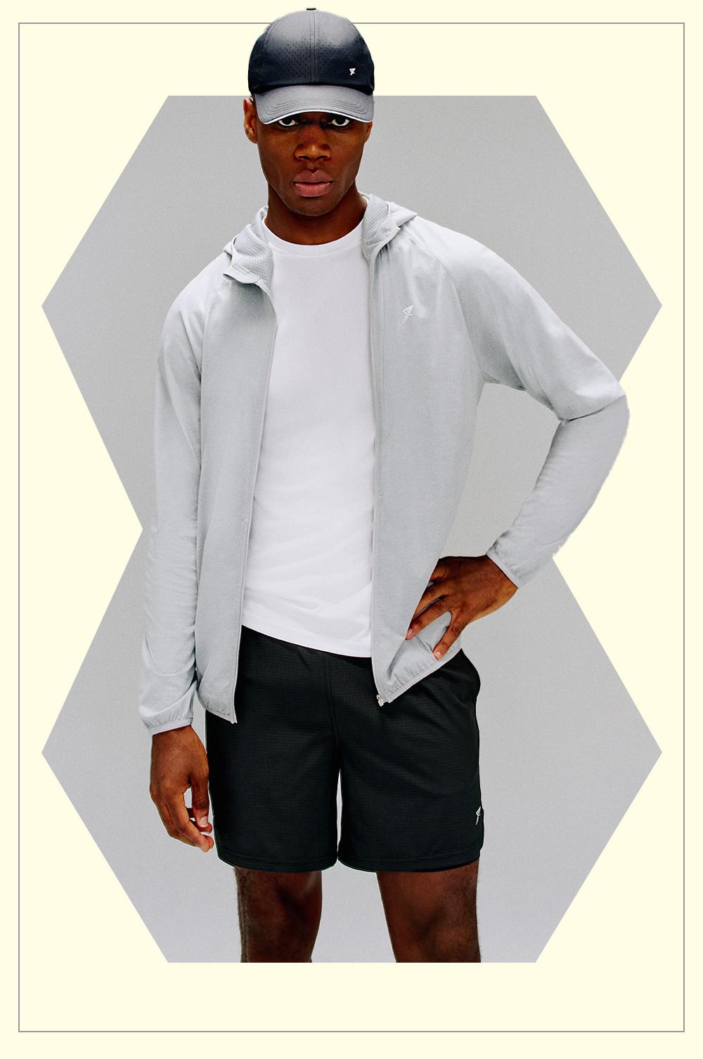 Model wears black shorts with grey hoodie and a cap