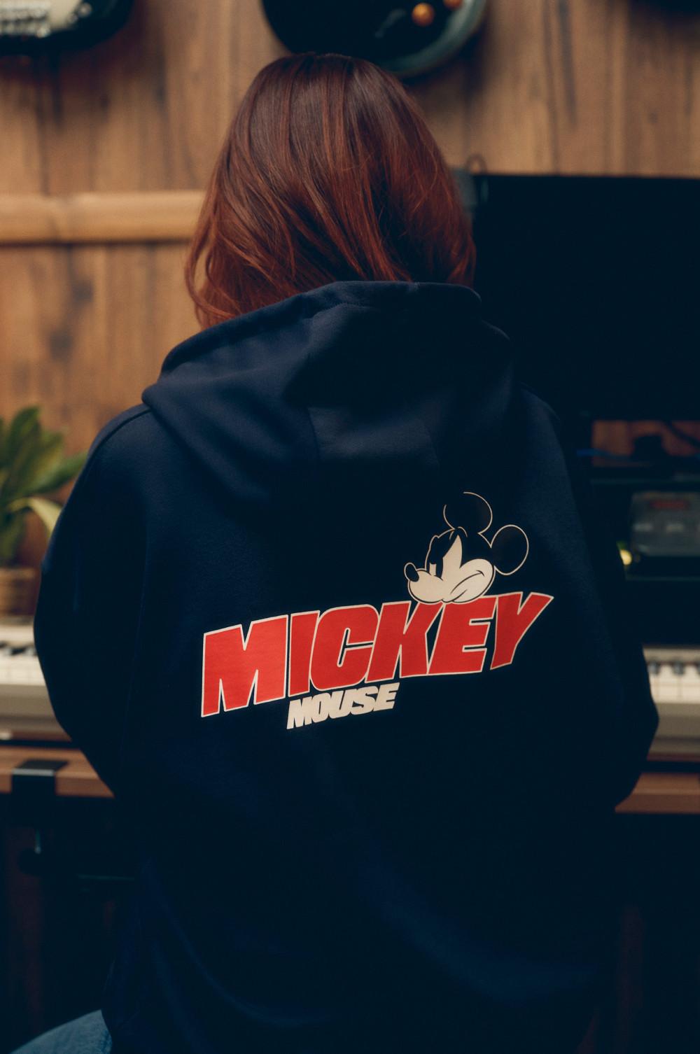Back view of person wearing navy hoodie with Mickey Mouse graphic and text on the back.
