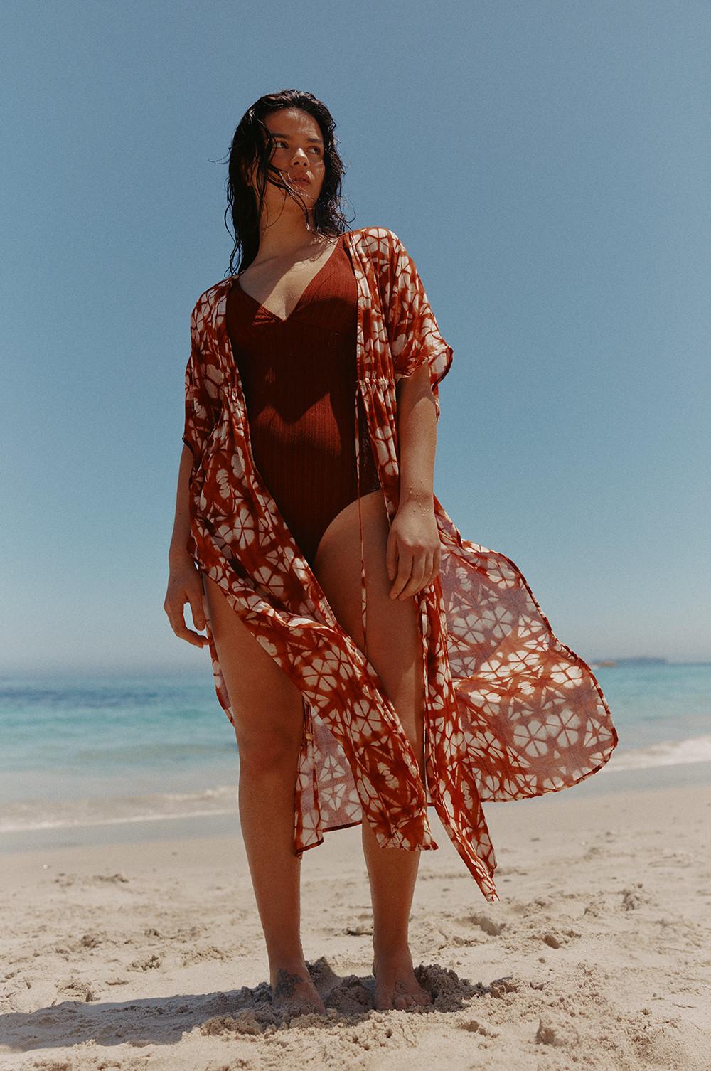 Model wears rust swimsuit with printed kimono