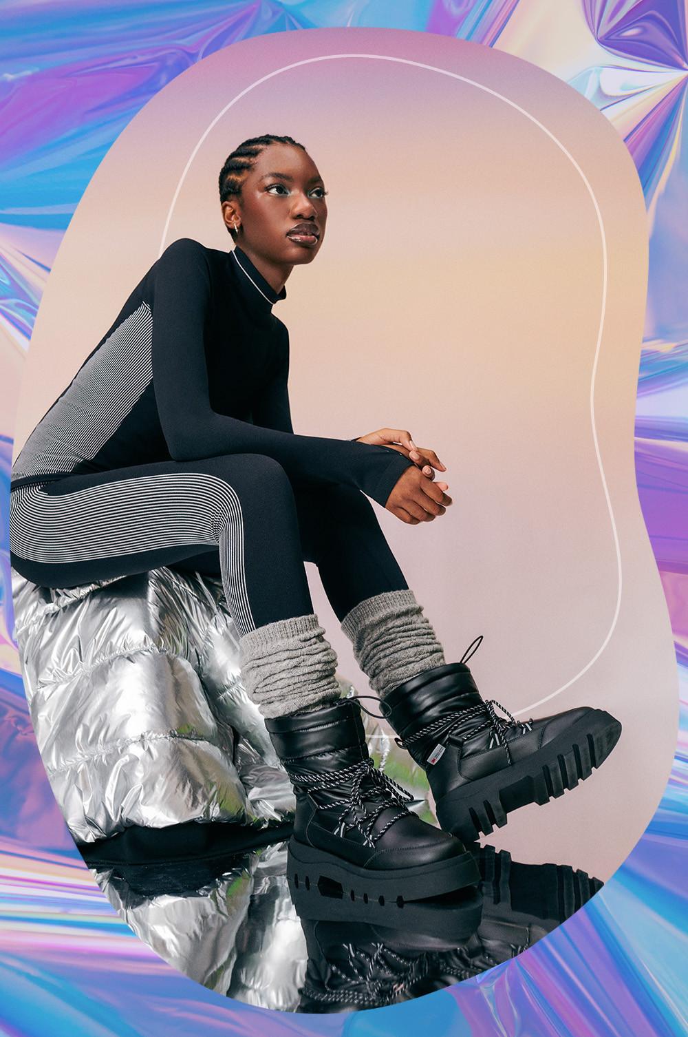 Model in Thermo-Oberteil und -Leggings mit grauen Stulpen und schwarzen Stiefeln