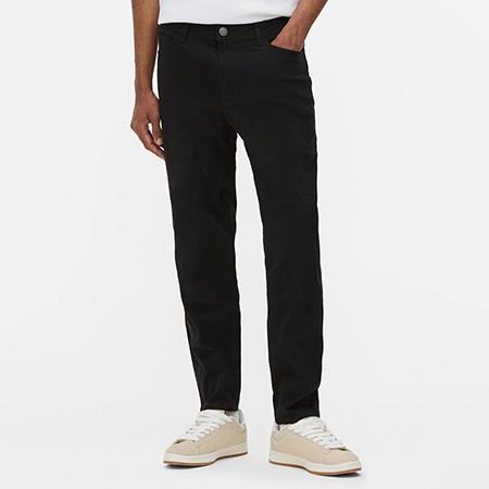 Black corduroy trousers with straight leg fit worn with white trainers and white top.
