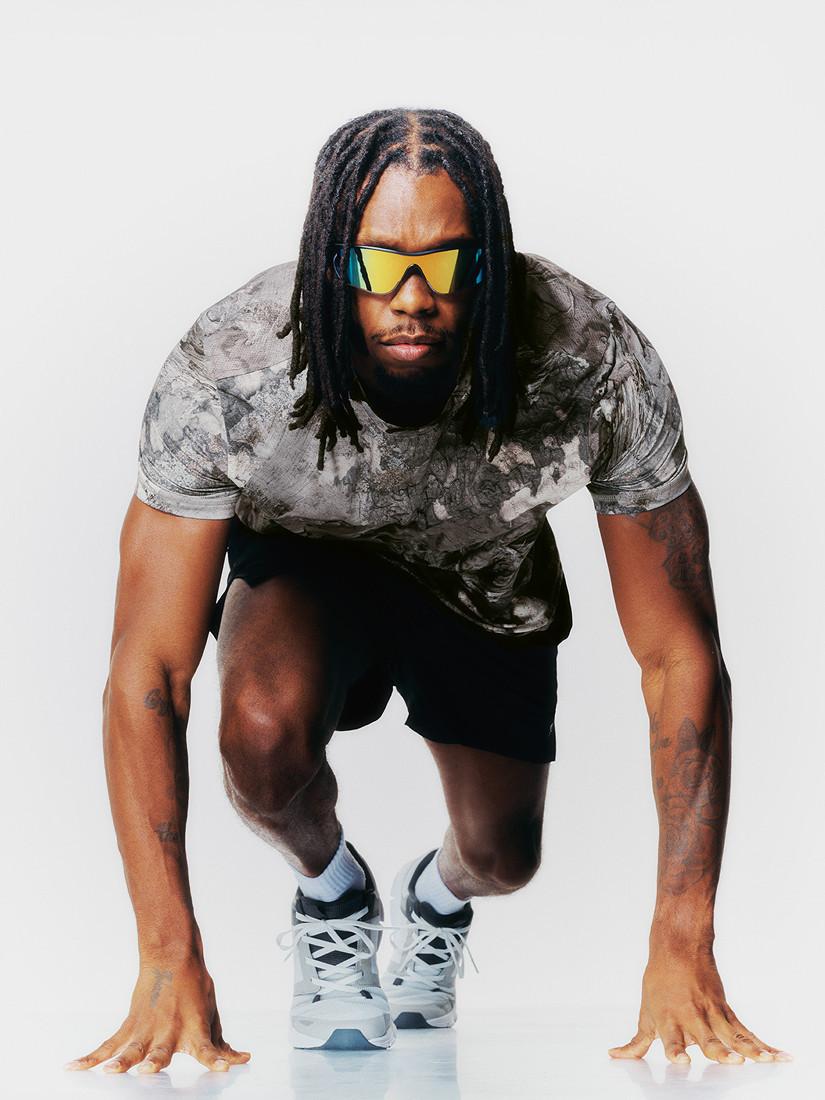 Person wearing sporty attire with yellow-tinted sunglasses in starting position for sprint.