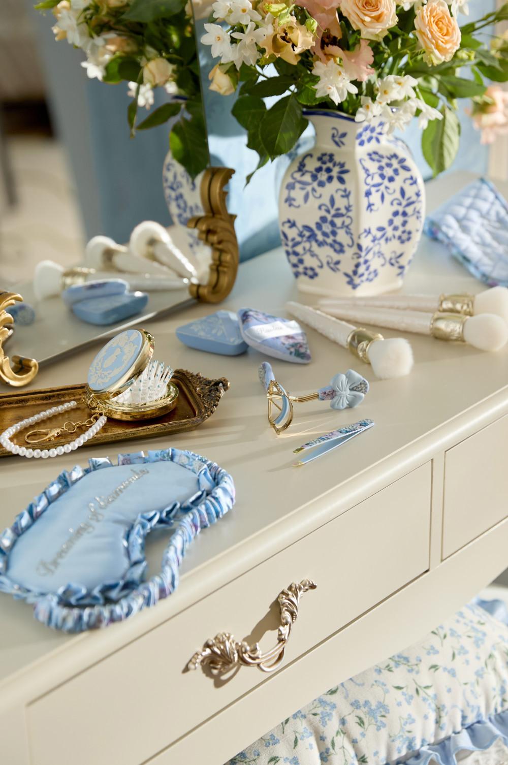 Elegant dressing table with blue and white porcelain vase, makeup brushes, pearl bracelet and decorative accessories.