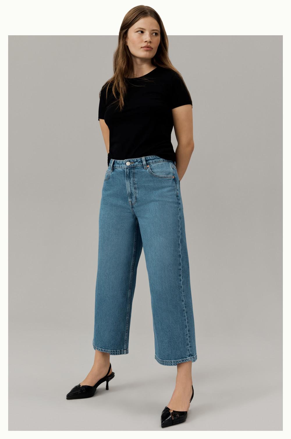 Person wearing black t-shirt with wide-leg cropped denim jeans and black pointed slingback heels.