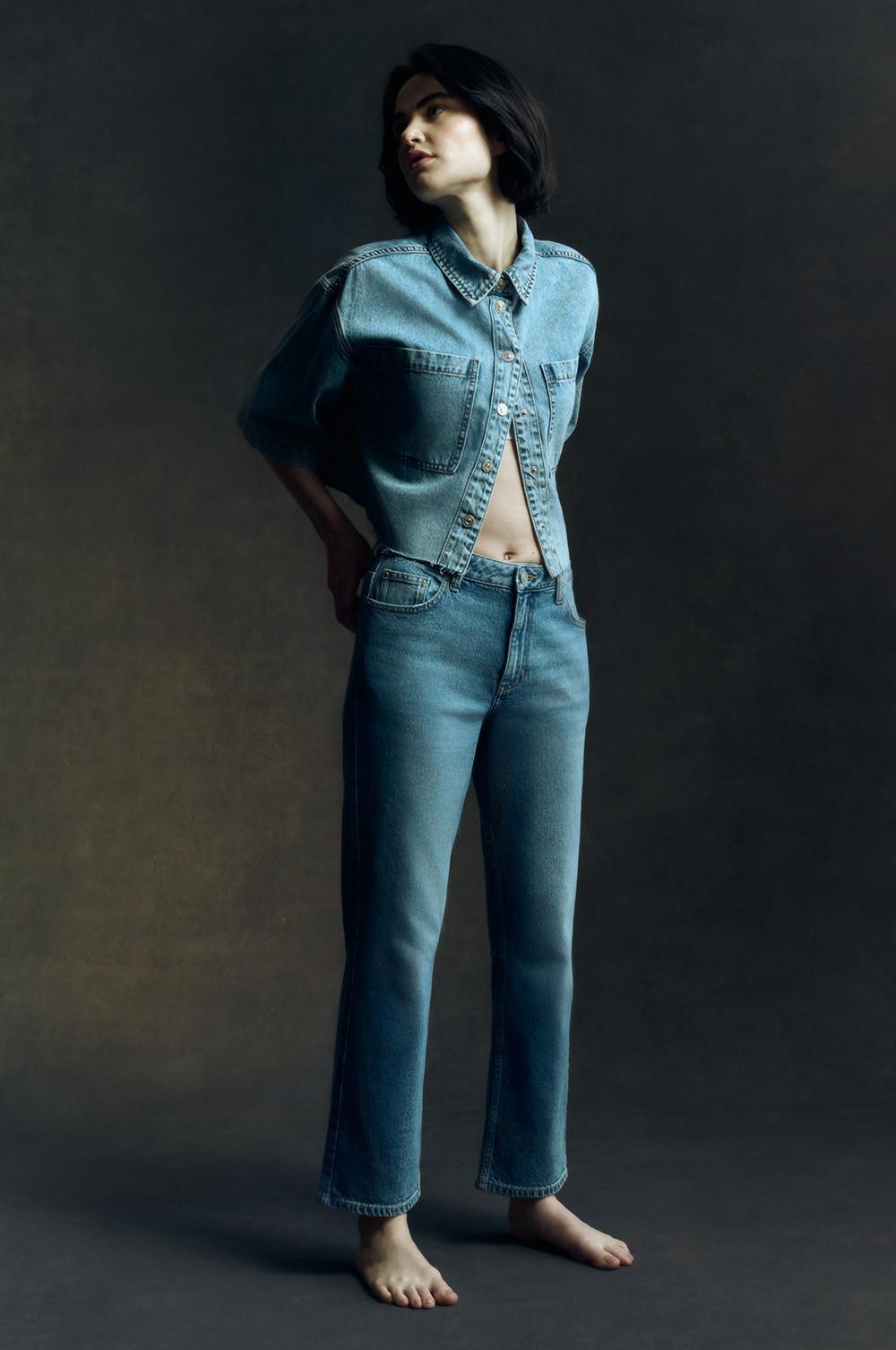 Cropped denim jacket and straight leg jeans shown barefoot in artistic lighting.