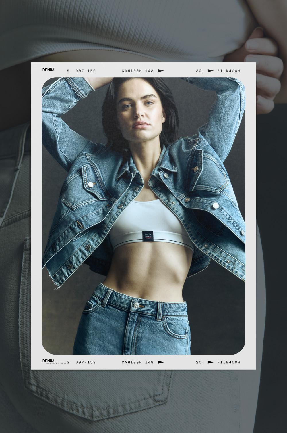 Model in light blue denim jacket, white sports bra, matching jeans in fashion photo format.