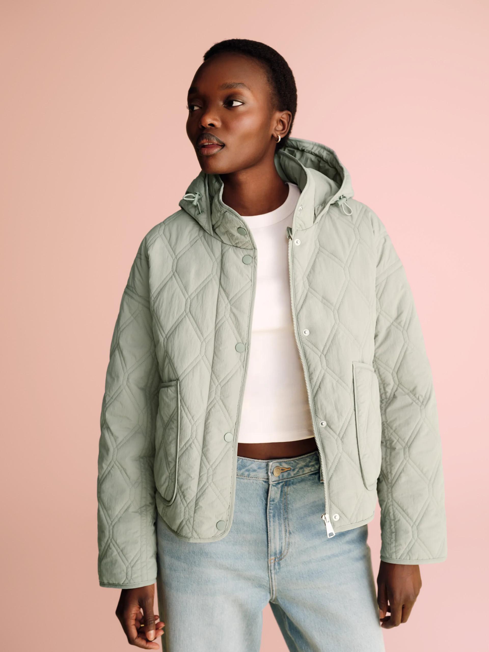 Mint green quilted jacket with hood, worn with white crop top and light denim jeans.