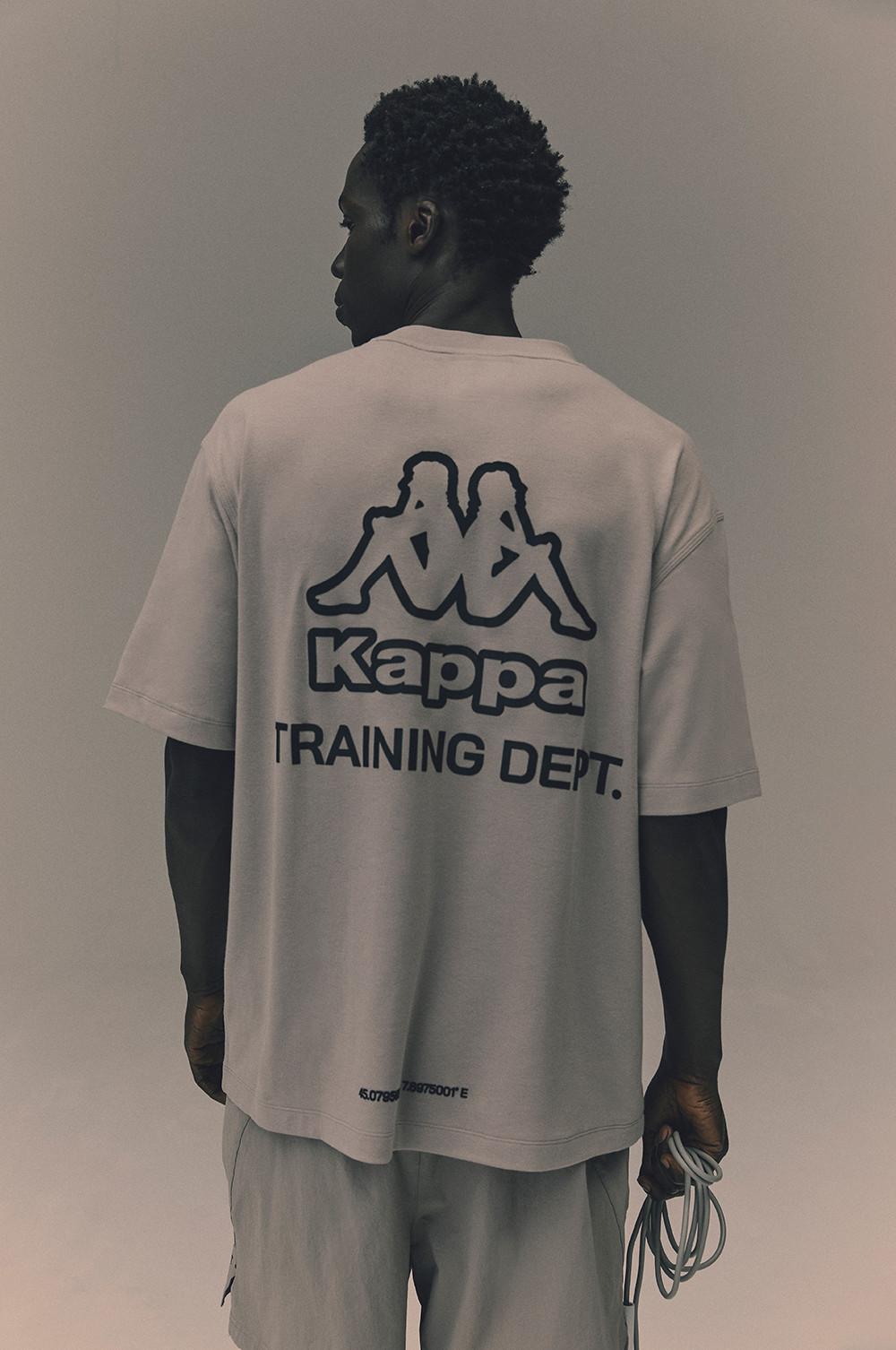 Model in weißem T-Shirt mit großem Kappa-Logo auf dem Rücken und grauen Shorts