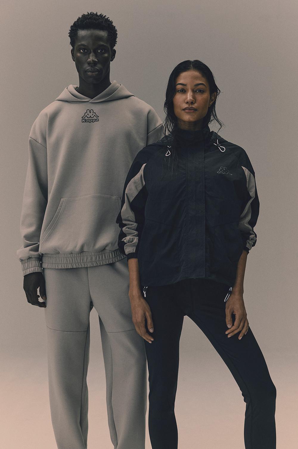 Kappa x Primark-Kollektion mit grauem Trainingsanzug mit Hoodie und schwarzer Trainingsjacke mit passender Hose in Studioaufnahme.