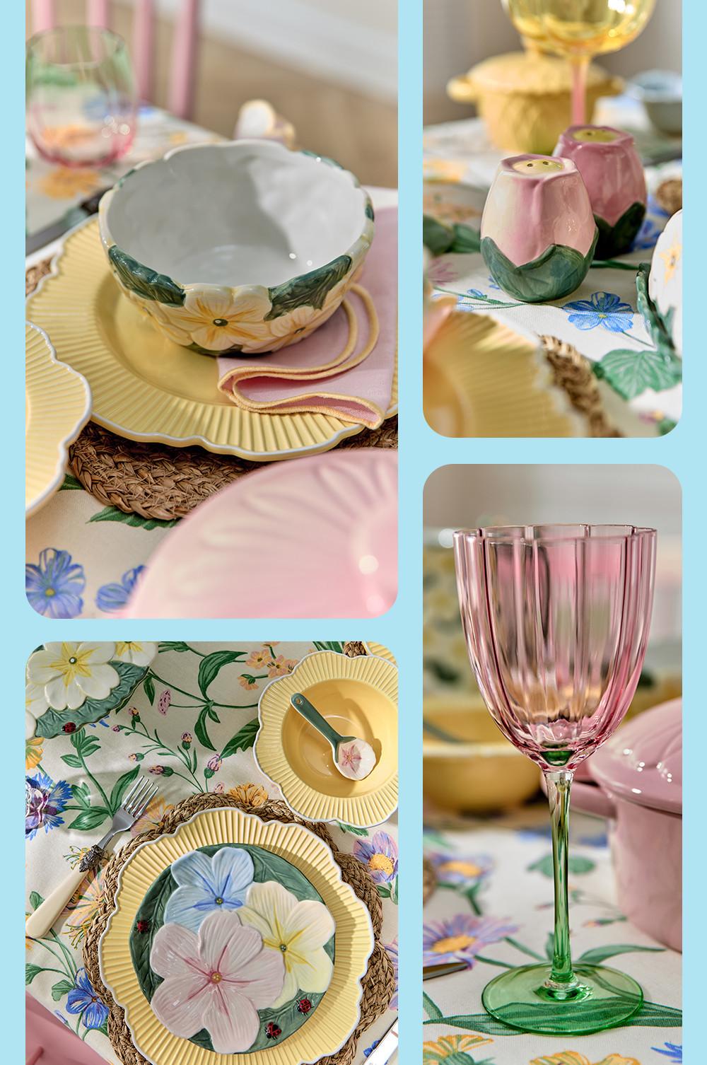 Floral tableware collection with flower patterned bowls, pink rose-shaped salt and pepper shakers, and pink and green wine glass on floral cloth.