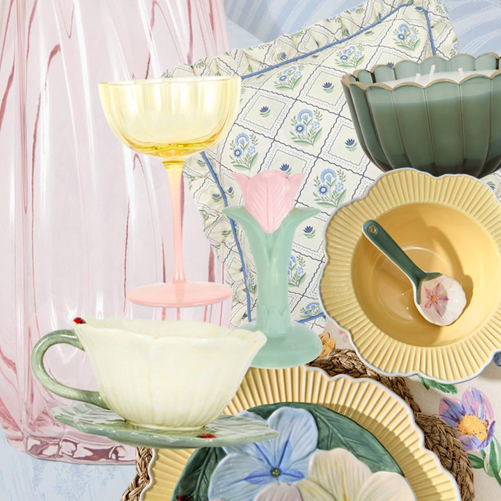Pastellfarbene Haushaltswaren-Collage mit Tellern mit Blumenmuster, gelbem Weinglas und mintgrüner Vase mit rosa Tulpe vor geblümtem Stoff.