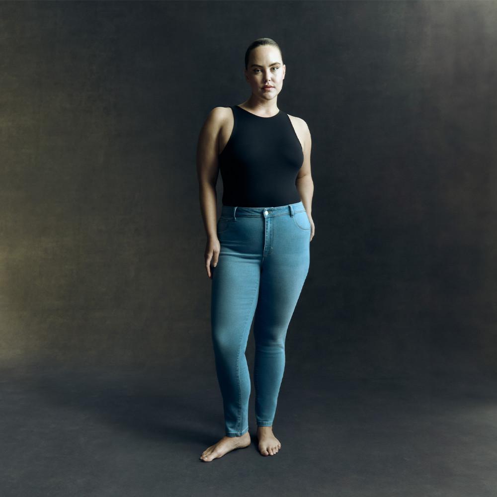 Model wearing blue skinny jeans and black vest top