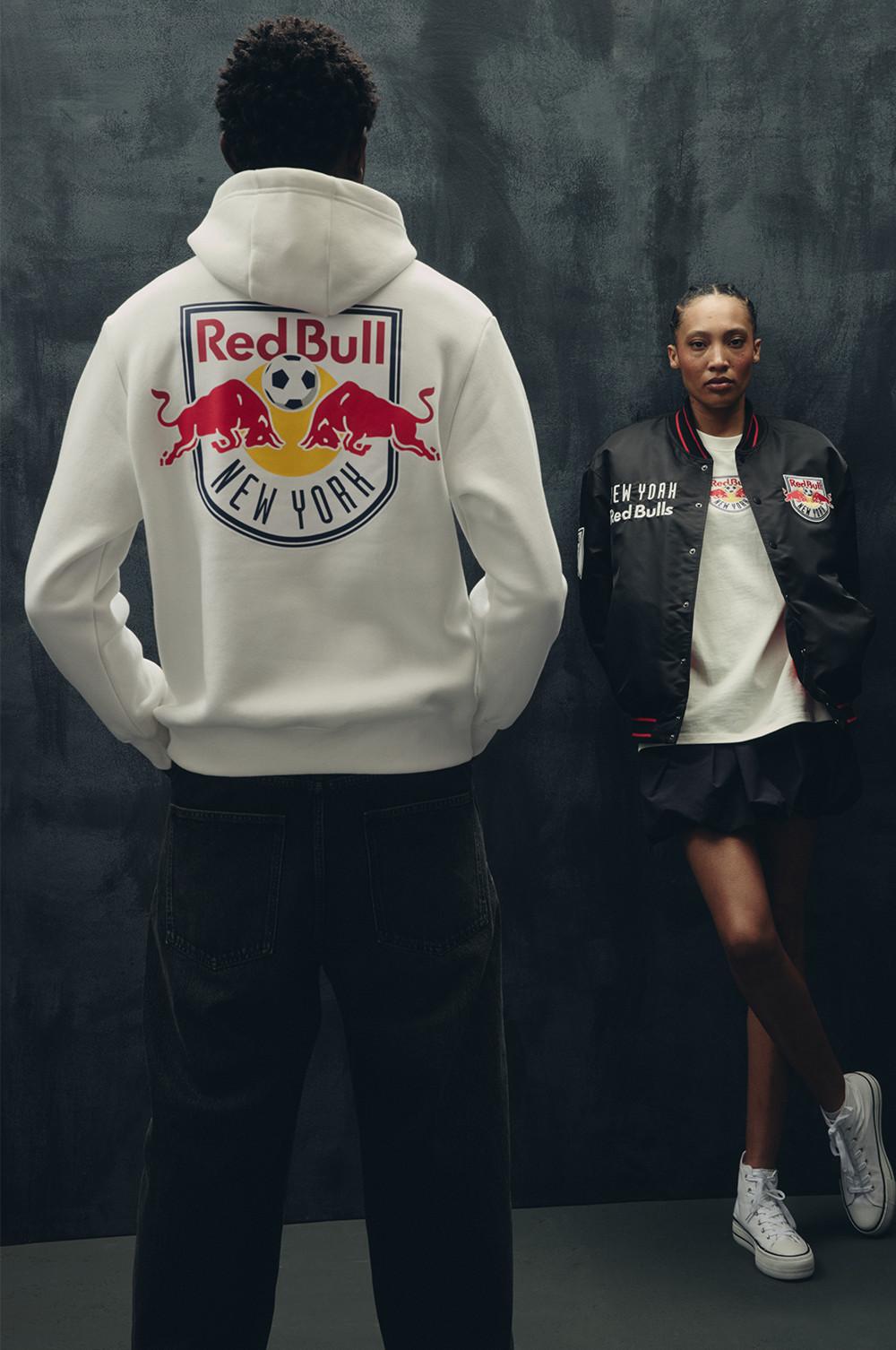 Weißer „Red Bull New York“ Hoodie mit großem Teamlogo von hinten gesehen neben einer schwarz-weißen College-Jacke.