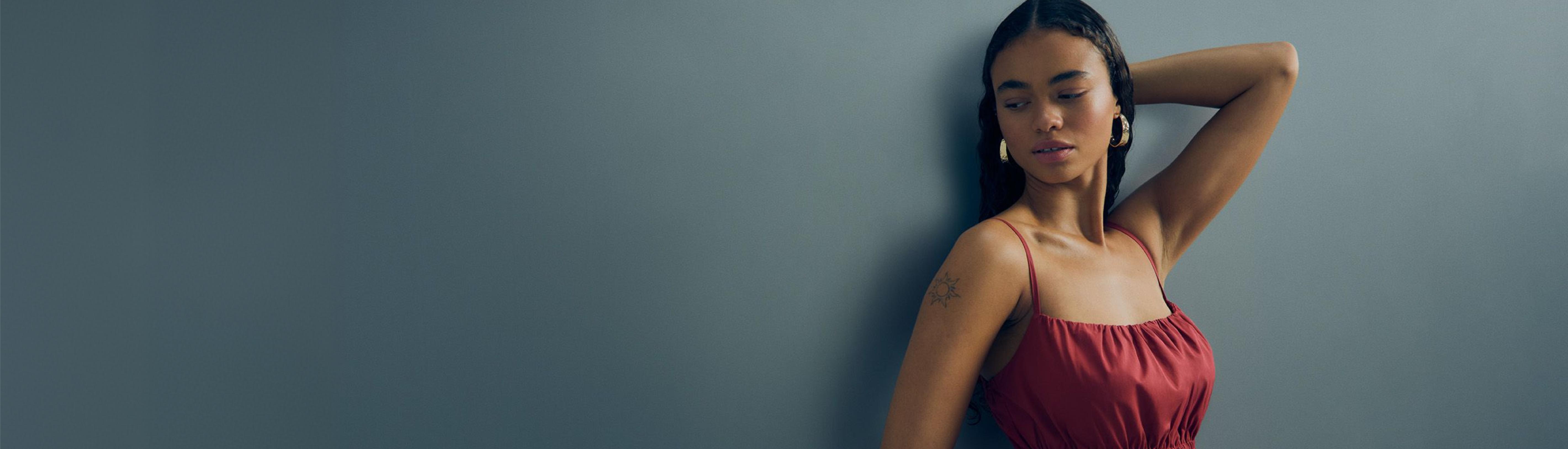 Three women wearing sports bras and white shorts smiling together for Breast Cancer Now charity campaign. Claude: Three women in sports bras and white shorts smiling together with Breast Cancer Now logo visible.