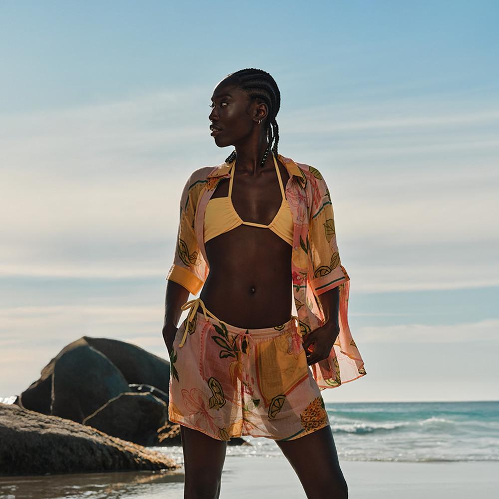 Model wearing a yellow bikini top with printed shorts and shirt