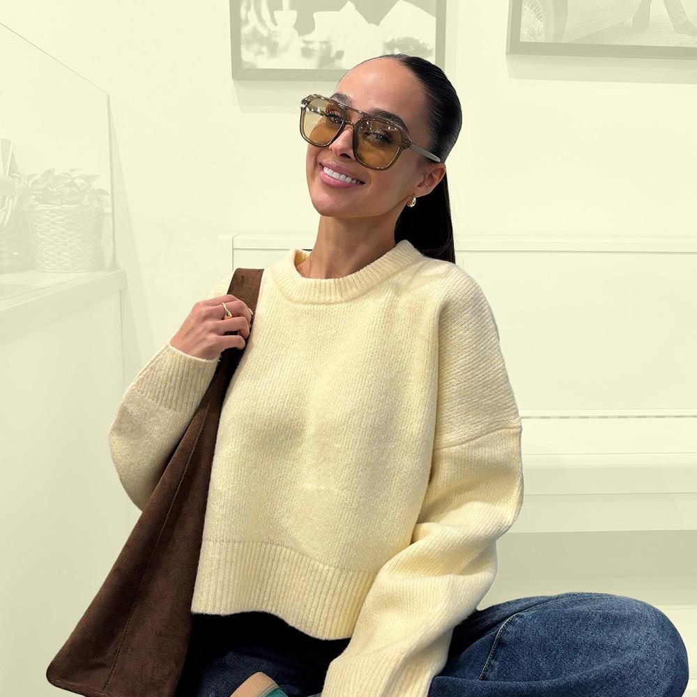 Model wearing yellow cropped sweater and blue jeans with brown tote bag