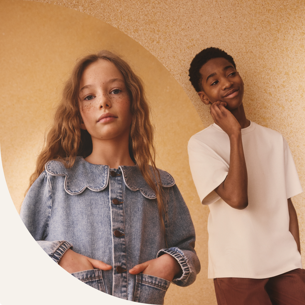 Ragazza che indossa una giacca di jeans con colletto smerlato e ragazzo con una maglietta bianca mentre posano insieme.