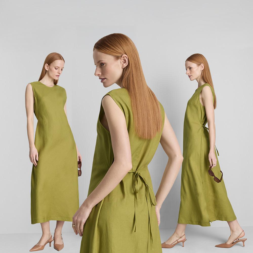 Three women walking arm-in-arm wearing summer dresses – floral print, white with blue flowers, and gold – carrying handbags on a sunny day.