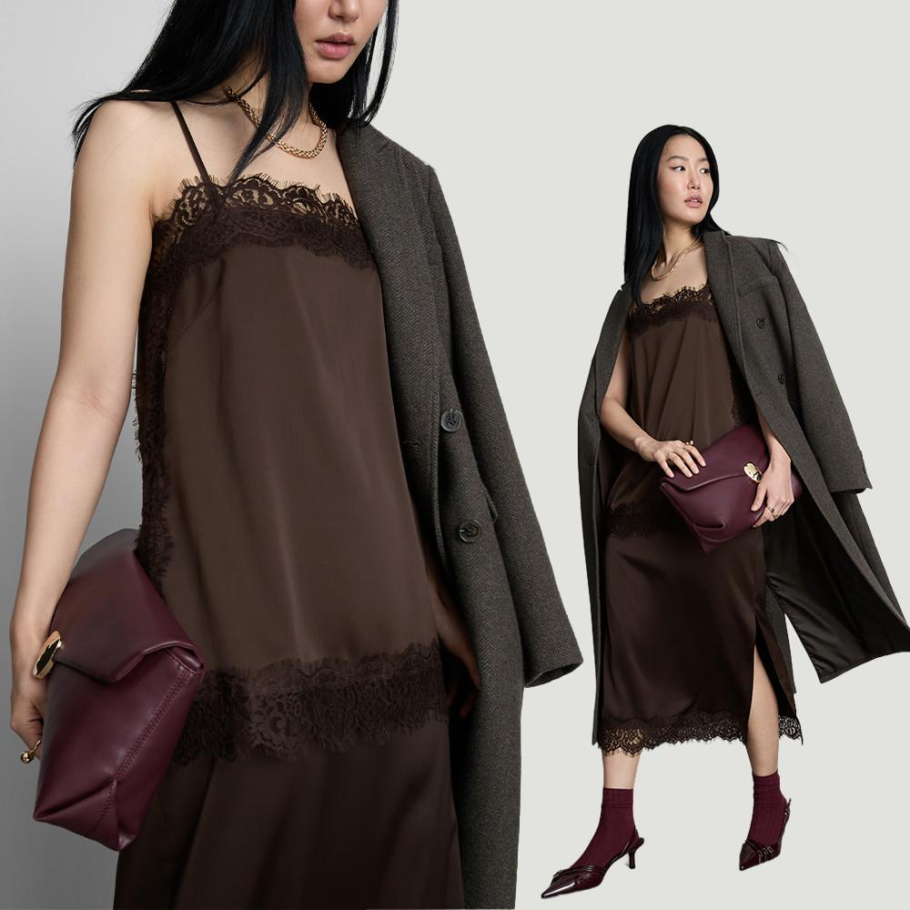 Persona con un lujoso abrigo de pelo marrón, pantalón negro y bandolera, en la calle de una ciudad en otoño.