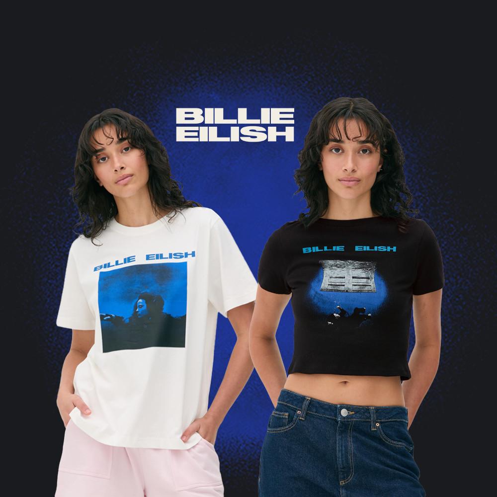 Two Billie Eilish T-shirts displayed on models - white oversized style with blue graphic and black cropped version with blue text against blue background.