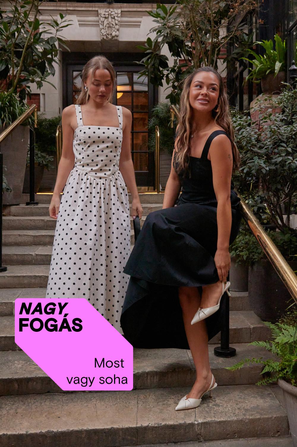 Két modell egy lépcsőn, az egyikőjük fehér pöttyös, a másik fekete ruhában, fehér cipőkben.