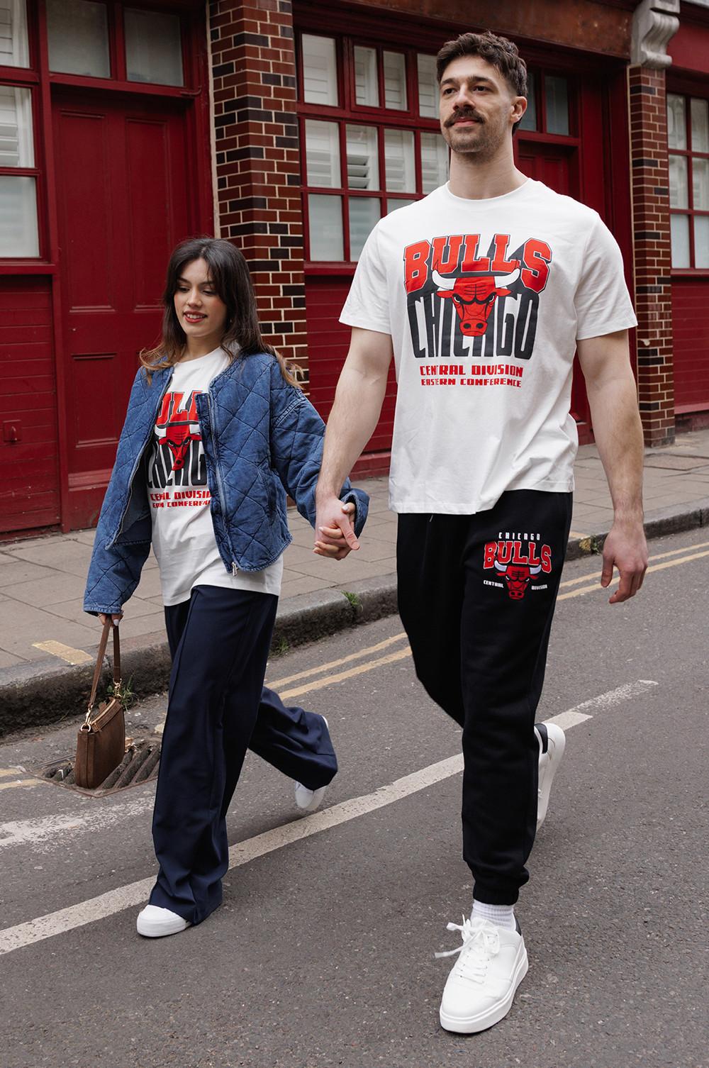 Models wearing a white Chicago Bulls graphic t-shirt with trousers and trainers