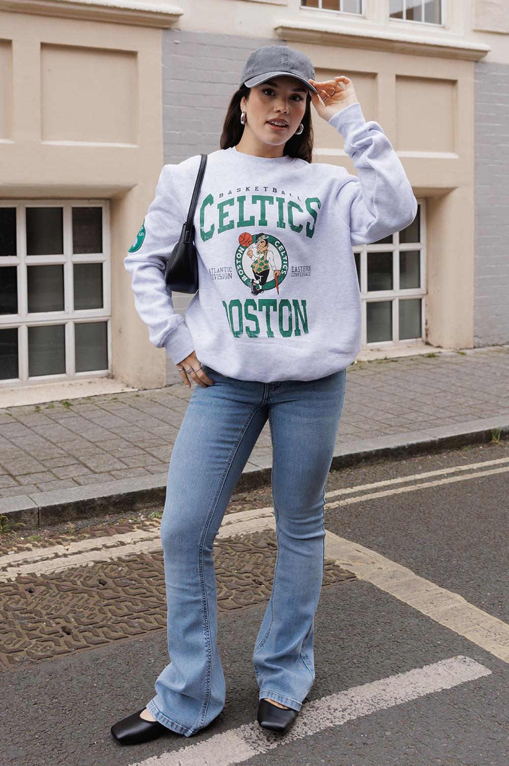 Model wearing a Celtics sweatshirt with jeans, cap and trainers