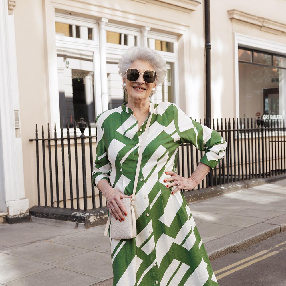 Model wearing green and white geometric print shirt dress with crossbody bag, worn with oversized sunglasses.