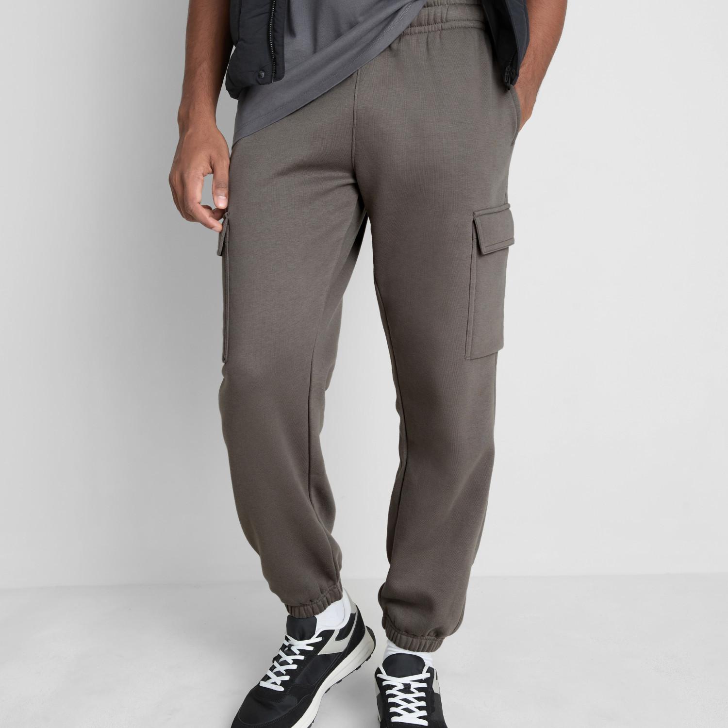Model wearing grey cargo joggers with elasticated cuffs and side pockets, paired with trainers.