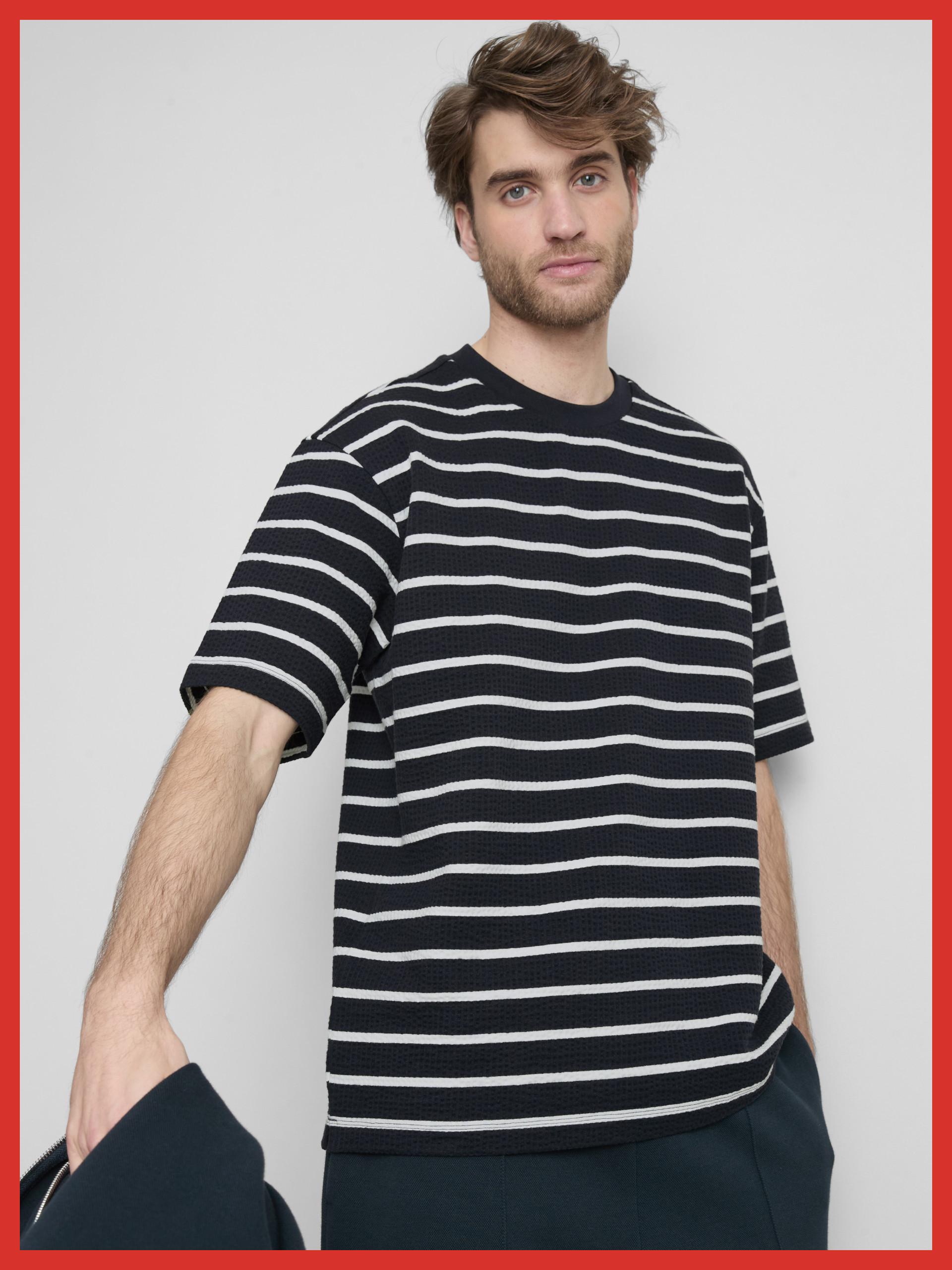 Model wearing a black and white striped short-sleeved t-shirt with a textured fabric finish.