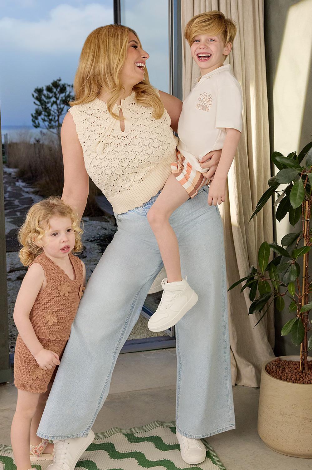 Stacey Solomon con un top de crochet y vaqueros, niña con un conjunto de crochet a juego en marrón claro y niño con una camiseta blanca, pantalones cortos a rayas y deportivas