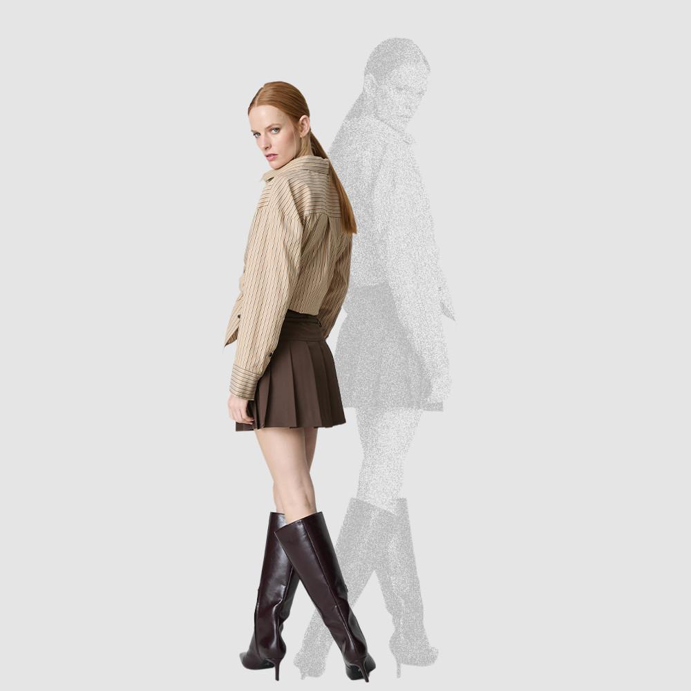 Model wearing beige striped shirt, brown pleated skirt and knee-high burgundy leather boots.