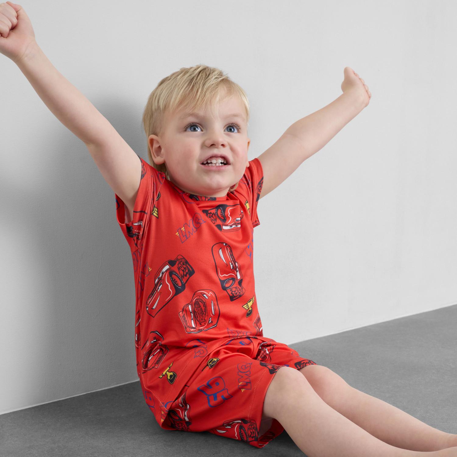 Child wearing blue and white striped Spider-Man pyjama set with matching shorts, arms raised playfully.