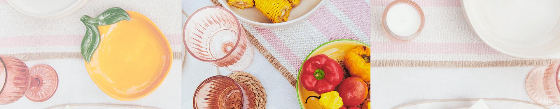Table set with summery tableware including woven floral mats and fruit shaped dish plates.