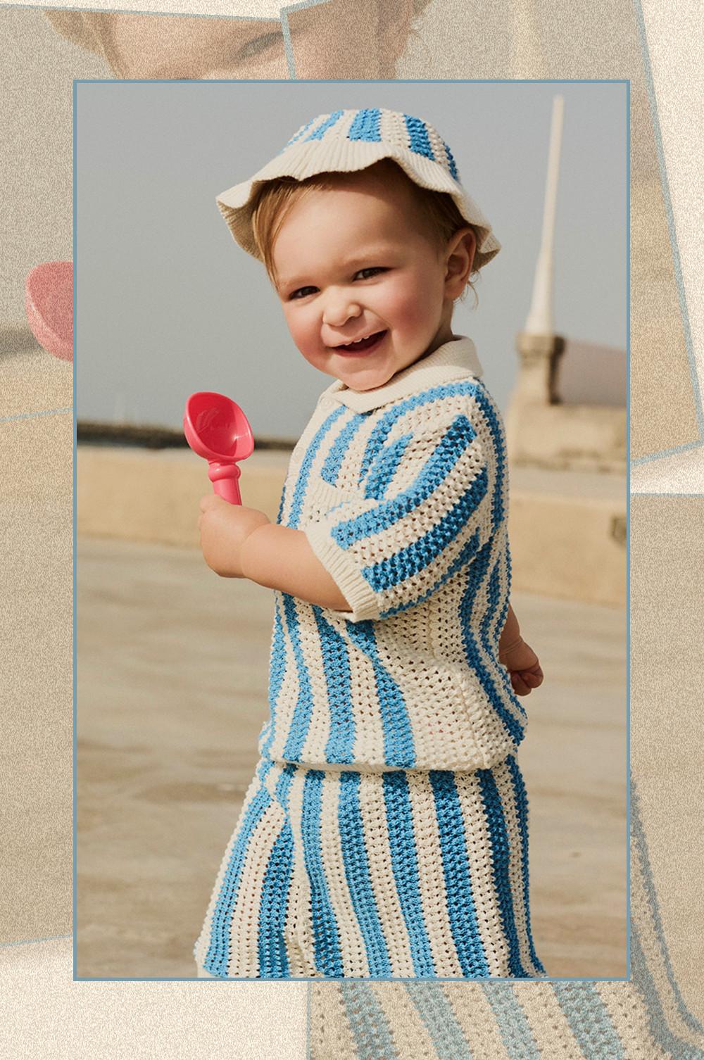 Child wearing blue and cream striped knit co-ord set with matching bucket hat, holding a pink spade.