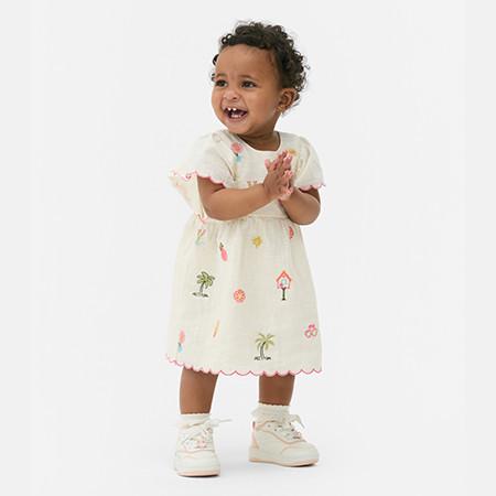 Baby wearing white dress with tropical print details