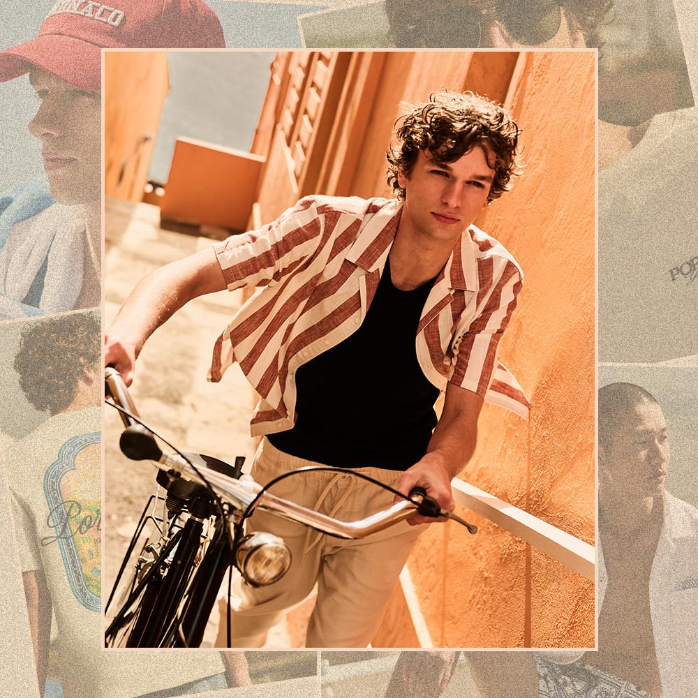 Model sitting on a motorbike wearing a brown and cream striped short-sleeve shirt over a black T-shirt.