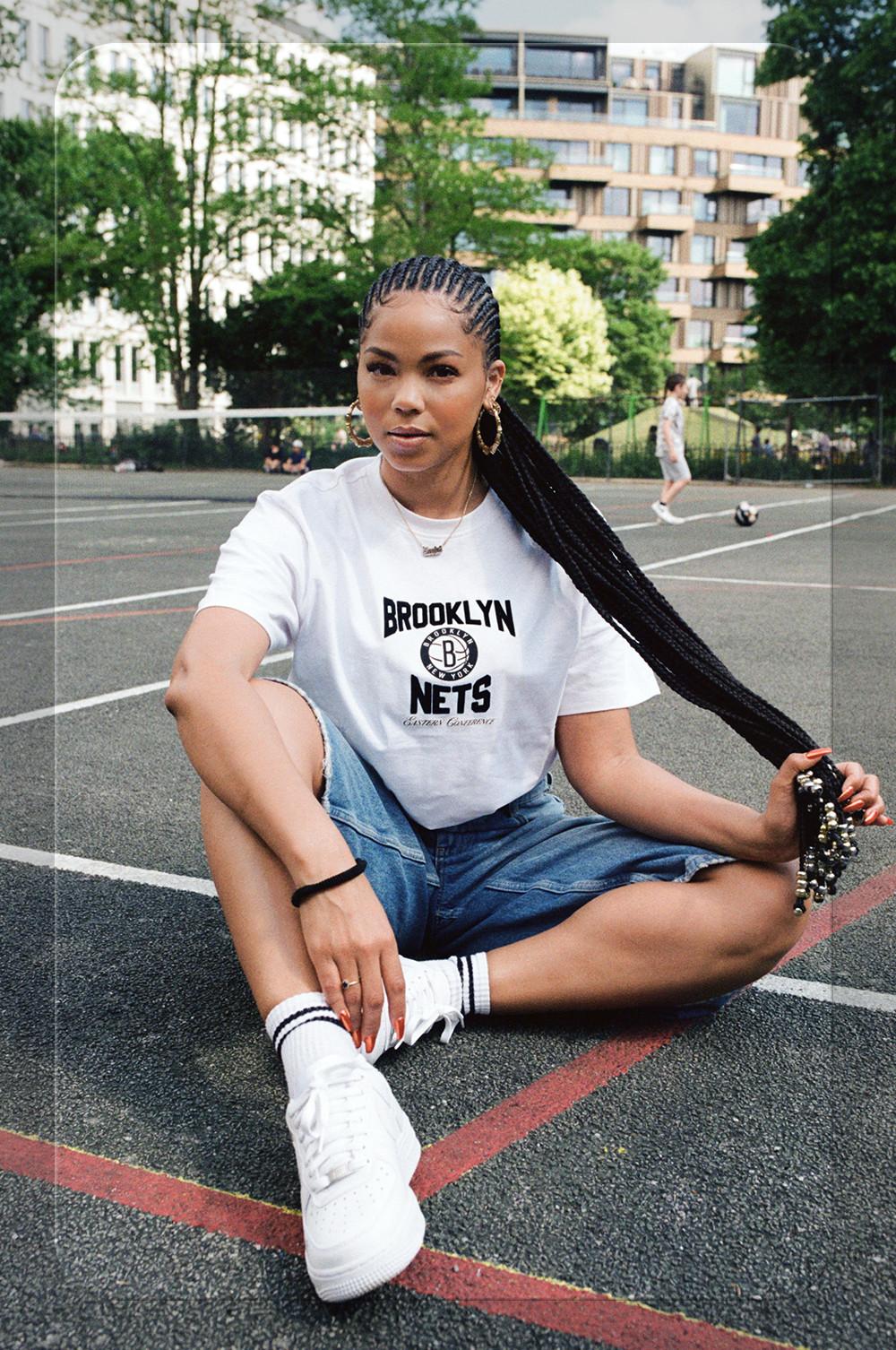 Model wearing a white graphic tee, denim shorts and trainers