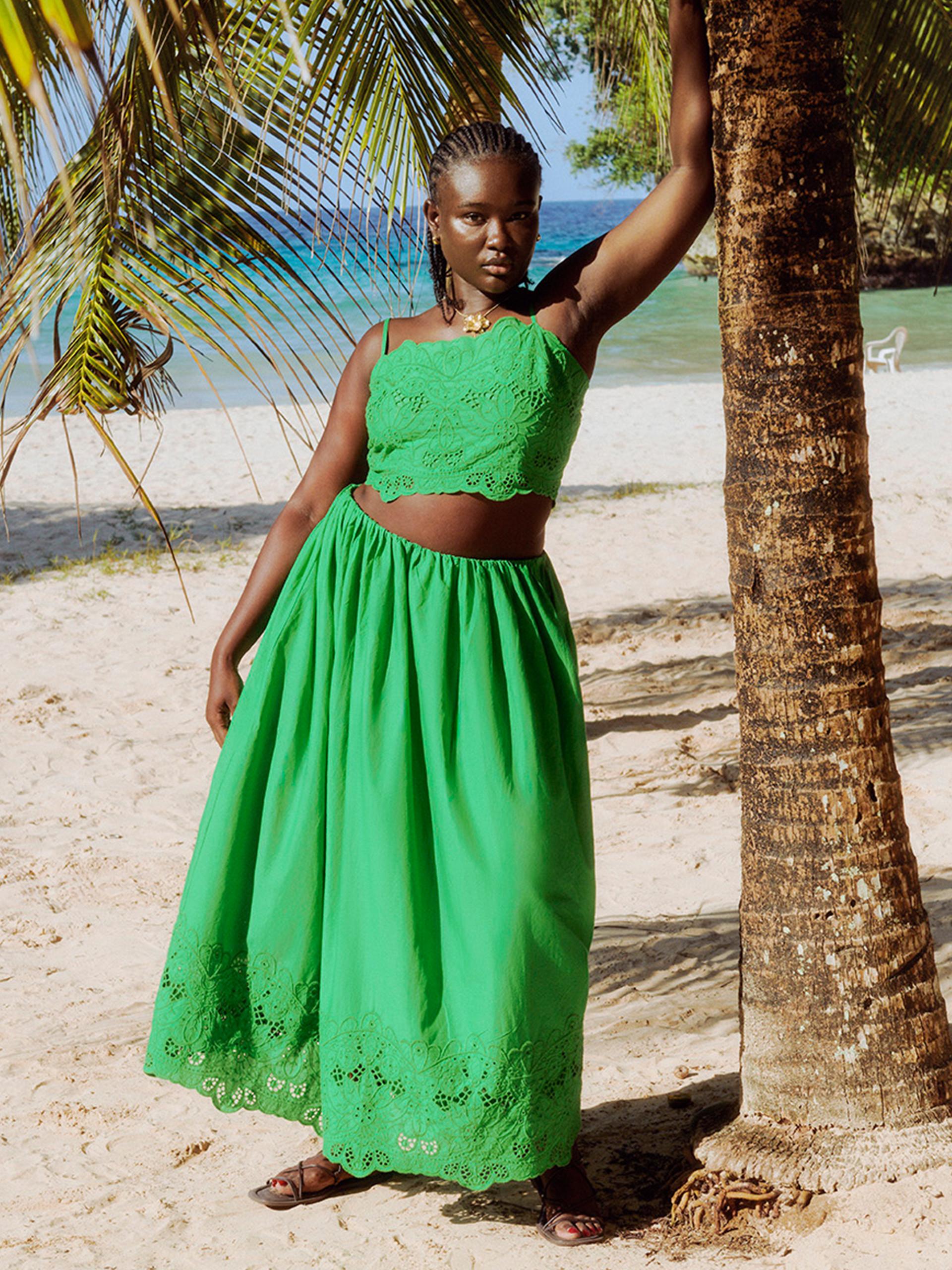 Model wearing green co-ord leaning on a palm tree